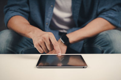 Midsection of man using mobile phone while sitting on table