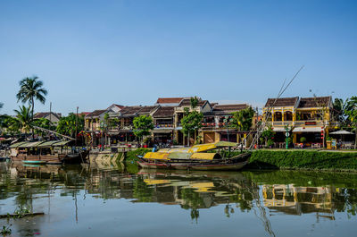 Boats moored in lake by buildings against clear sky