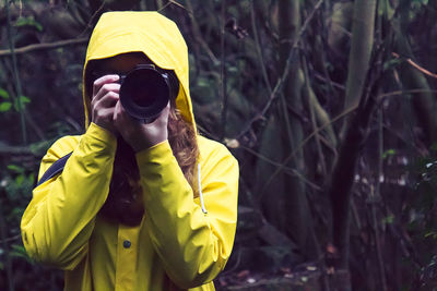 Young woman photographing while standing in forest