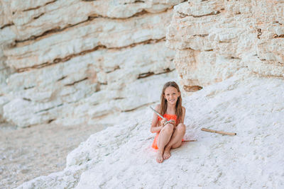 Portrait of young woman sitting on rock