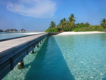 Swimming pool by sea against blue sky