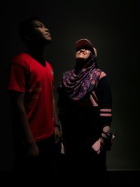 Young couple standing against black background