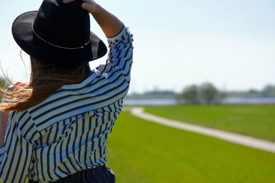 Rear view of person standing on field against sky