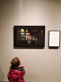 Rear view of woman standing against wall at home