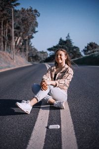 Portrait of young woman sitting on road