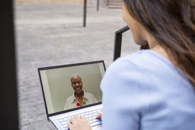 Businesswoman video calling through laptop while sitting outdoors