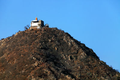 Low angle view of historic building on mountain against clear blue sky