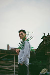 Portrait of young man holding leaf while standing outdoors