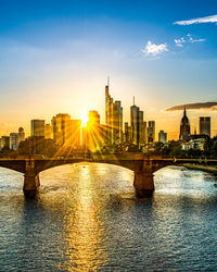 River by buildings against sky during sunset