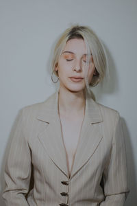 Close-up of young woman wearing blazer against wall