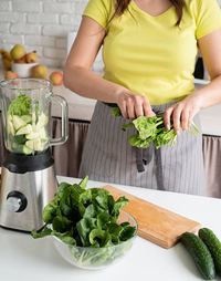 Healthy eating and dieting. young brunette woman making green smoothie at home kitchen