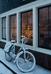 Bicycle by window of house during winter