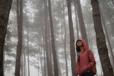 Woman standing by trees in forest during winter