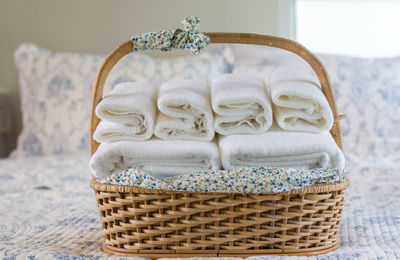 Close-up of towels in wicker basket on bed at home