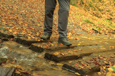 Low section of man standing on water during autumn