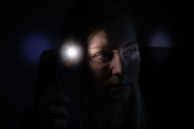 Woman holding flashlight looking away in darkroom