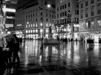 People walking on illuminated street at night