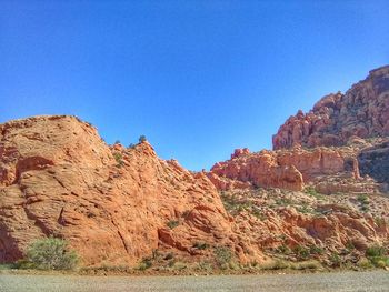 Rock formations on landscape against clear blue sky