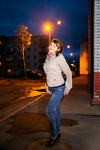 Woman standing on illuminated street at night