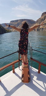 Rear view of woman standing by railing against sky