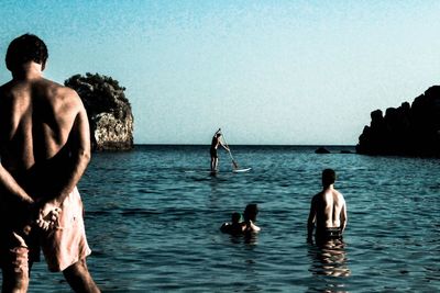 Rear view of friends standing on beach