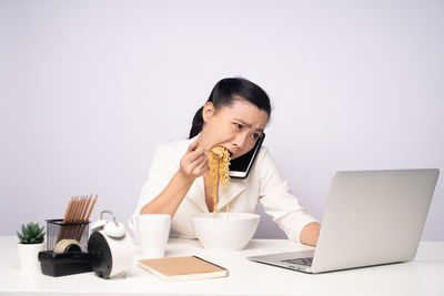 Young woman using phone while sitting on table