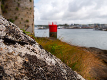 Lighthouse on rock by sea against sky