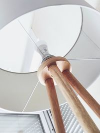 Low angle view of electric lamp against white wall
