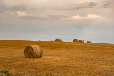 Hay bales on field against sky