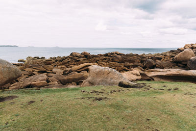 Rocks on shore by sea against sky