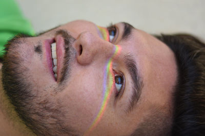 Close-up of smiling man with spectrum on face looking away