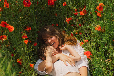 Happy mother's day. little boy and mother is playing in a beautiful field of red poppies