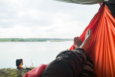 Midsection of woman lying down in lake against sky