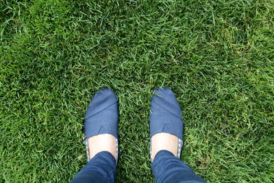 Low section of woman standing on grassy field