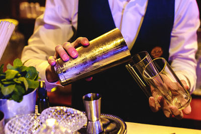Midsection of bartender pouring cocktail