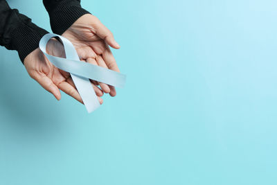 Close-up of hand holding blue over white background