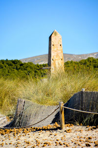 Built structure on field against clear blue sky