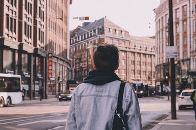 Rear view of man on city street amidst buildings