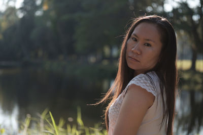 Portrait of young woman with lake in background