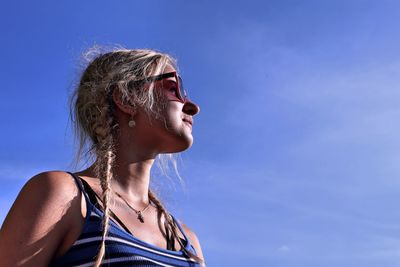 Low angle portrait of woman against blue sky