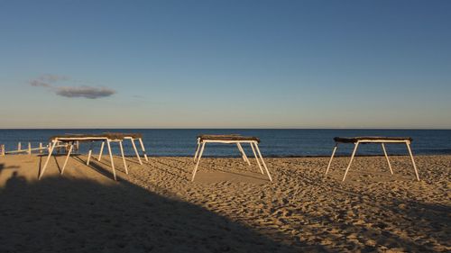 Deck chairs on beach against clear sky