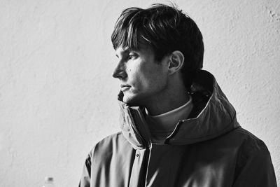 Portrait of young man looking away against wall