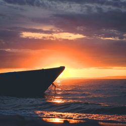 Silhouette boat in sea against sky during sunset