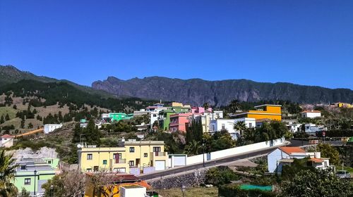 High angle view of buildings in city against clear blue sky