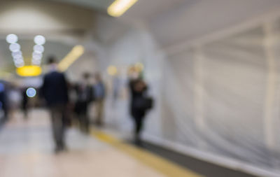 Defocused image of people walking in illuminated railroad station