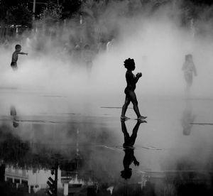 Silhouette man and woman standing in water against sky