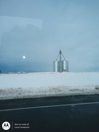 Scenic view of road by field against sky