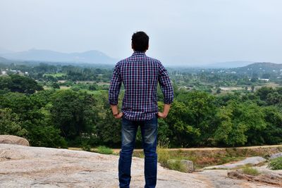 Rear view of man standing on mountain against sky