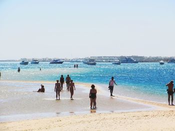 People on beach against clear sky