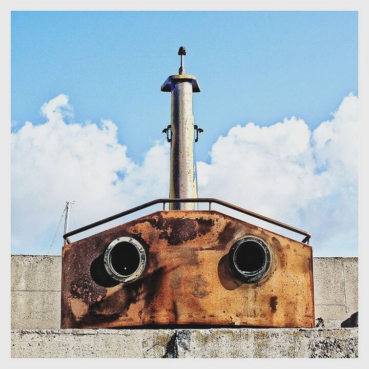 LOW ANGLE VIEW OF BIRD ON ABANDONED BUILDING AGAINST SKY